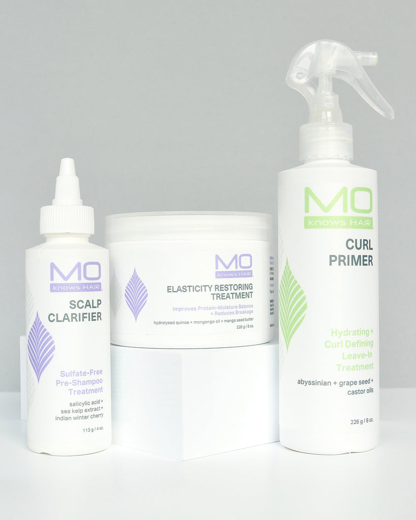 Set of MoKnowsHair products including Scalp Clarifier, Elasticity Restoring Treatment, and Curl Primer on a gray background.