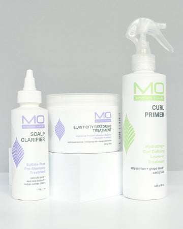 Set of MoKnowsHair products including Scalp Clarifier, Elasticity Restoring Treatment, and Curl Primer on a gray background.